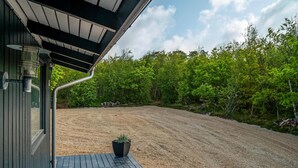Un espacio al aire libre cubierto con suelo de grava, una terraza de madera y una planta en maceta.