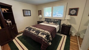 A bedroom with a bed, two nightstands, a dresser, a window with blinds, and a rug.