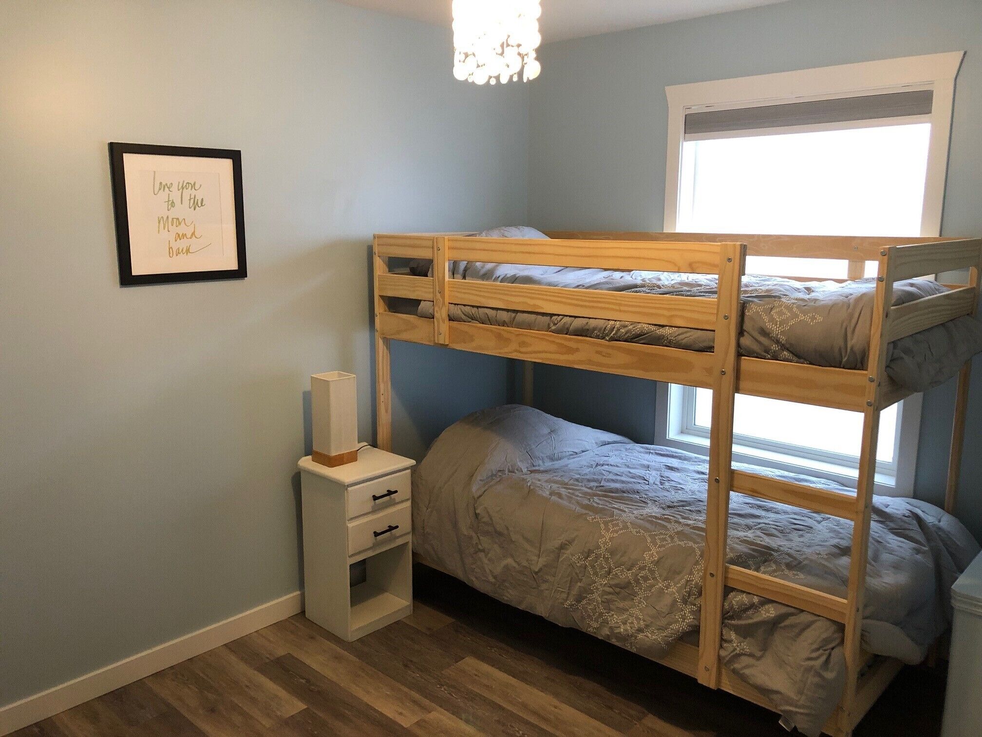 A bunk bed room with a small bedside table and a framed picture on the wall.