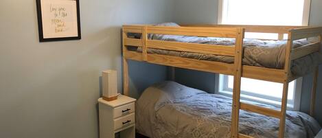 A bunk bed room with a small bedside table and a framed picture on the wall.