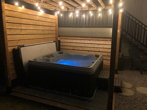 A hot tub in a wooden cabin with a staircase and a bench. - Cheerful, cozy 4 bedroom house w/ hot tub and firepit area (Red Deer)