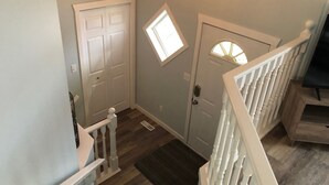 Un escalier avec des rampes blanches menant à une porte dotée d’une petite fenêtre.