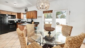 A modern kitchen with wooden cabinets, a black refrigerator, and a dining area with wicker chairs and a glass table. - ❤︎Families love the location and private, heated pool❤︎ 6-min walk to beach❤︎ (Destin)