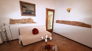 A room with a bed, a wooden table with candles, a painting, and a stained glass door.
