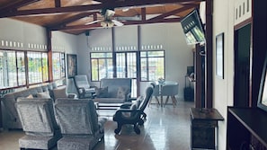 A spacious room with a high ceiling, large windows, and a ceiling fan. There are several chairs and a sofa arranged for seating. - BROWN CAT (Montenegro)