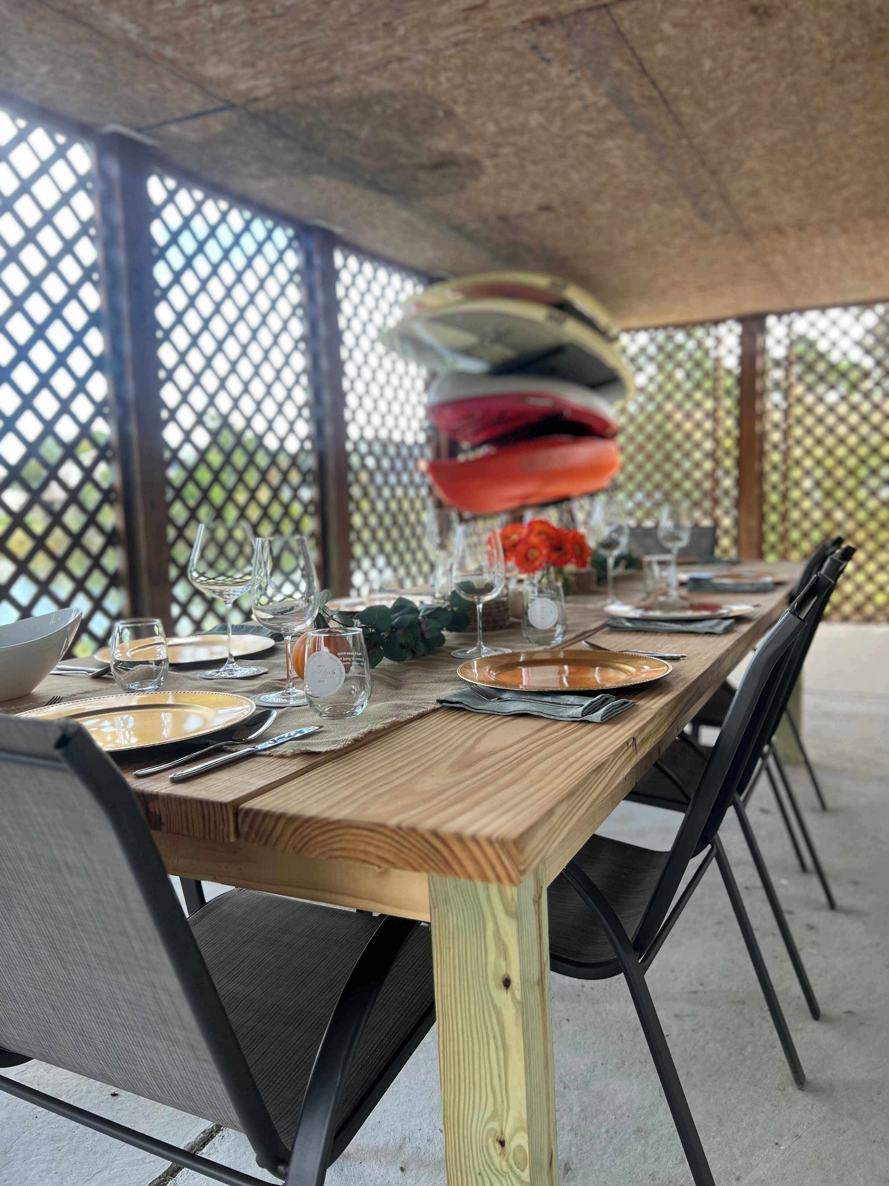 An outdoor dining area with a wooden table set for four, surrounded by chairs.