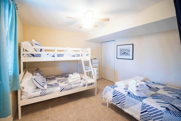A bunk bed with a ladder, a single bed, and a ceiling fan.