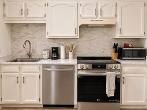A kitchen with white cabinets, a stainless steel dishwasher, a double oven, and a microwave. - Pet-Friendly King Bed Stay w/ Screened Porch // Pigeon Forge (Pigeon Forge)
