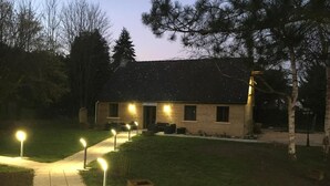 A two-story building with a sloped roof, a paved driveway, and a well-lit entrance. - Logis Hotel le Val Sarah (Bardouville)