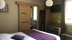 Een slaapkamer met een bed, een houten kledingkast, een bureau en een stoel.