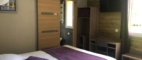 Un dormitorio con cama, un armario de madera, un escritorio y una silla.