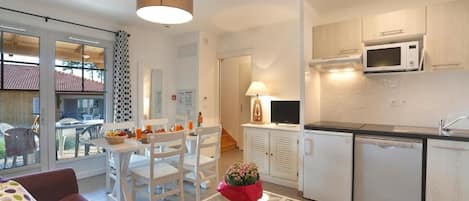 A compact living space with a kitchenette, dining area, and a glass door leading to an outdoor patio.