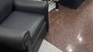 A modern lobby with a marble wall, two black leather sofas, a glass coffee table, and a small decorative table with golden accents. - Diplomat Hotel  (Buenos Aires)