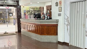 A hotel reception area with a marble wall, a reception desk, and a glass door entrance. - Diplomat Hotel  (Buenos Aires)