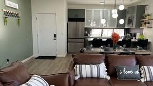 A modern living room with a brown leather sofa set, a dining area, and a kitchen with stainless steel appliances. - LuXury ZeN ZoNE (No Cleaning fee, King size bed). (Omaha)