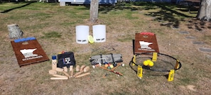 A lawn game setup with two wooden boards, a bag of wooden mallets, a bag of balls, and a croquet hoop. - Your lakeside oasis awaits: perfect for families and fun! (Hackensack)