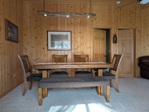 A wooden-paneled room with a dining table, chairs, a bench, a framed picture, and a door. - Your lakeside oasis awaits: perfect for families and fun! (Hackensack)