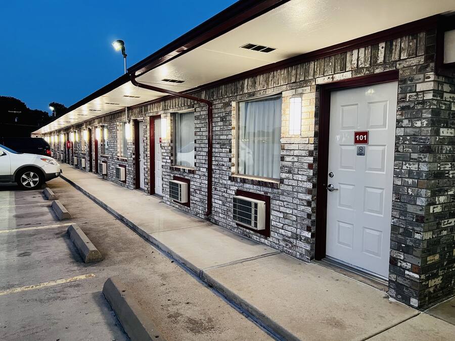 A motel with a row of rooms, each with a window and a door.