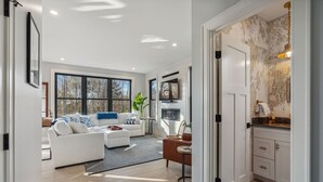 A modern living room with a white sofa, a brown armchair, and a fireplace.