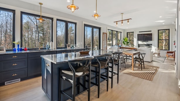 A modern kitchen with a large island, bar stools, and a dining area with a TV.