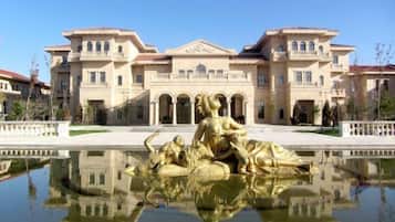 A large building with a reflective pool in front, featuring golden statues.