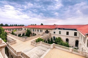 A courtyard with multiple buildings, a red-roofed structure, and a clear sky. - Avanna Hotel (Jungar Banner)