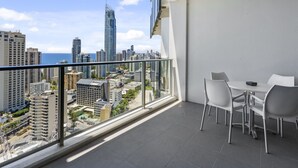Ein Balkon mit Blick auf die Stadt, einem Tisch mit Stühlen und einem Glasgeländer.