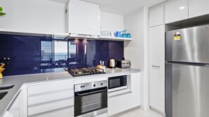 Eine moderne Küche mit weißen Schränken, einem Edelstahl-Kühlschrank, einem eingebauten Backofen und einem Gasherd.