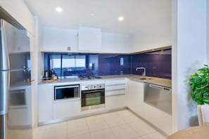 Uma cozinha moderna com eletrodomésticos de aço inoxidável, forno embutido e uma janela grande.