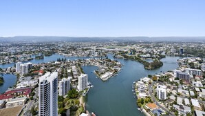A coastal cityscape with a river meandering through it, surrounded by residential and commercial buildings. - 53rd Floor - Sky High Apartment in Circle on Cavil (Gold Coast)