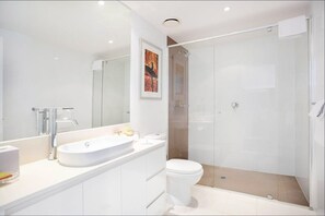 Features a sleek vanity with a large sink and a glass-enclosed shower with walk-in design.
