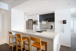 Enjoy casual dining at this kitchen with a central island, sink, and microwave, paired with stainless steel appliances and a telephone.