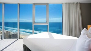A hotel room with a large bed, a view of the ocean, and a cityscape in the background. - Charming Level 35 Central Getaway (Gold Coast)