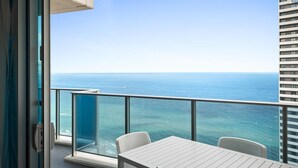 Un balcon avec vue sur l’océan, une table et des chaises.