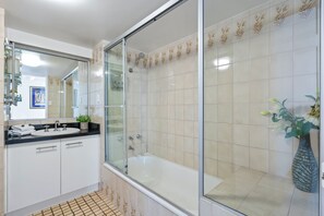 A modern bathroom with a glass-enclosed shower, a white bathtub, and a black countertop with a sink. - Full Ocean View Lvl21- 2Bed2Bath -Long Beach Apt (Surfers Paradise)