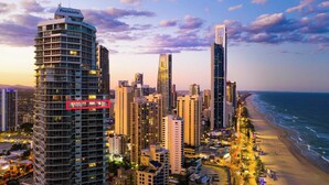 A coastal cityscape with high-rise buildings, a beach, and a clear sky.