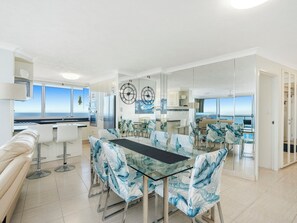 Enjoy ocean views from the comfort of this stylish space, featuring a dining table, sofa, and kitchen area.