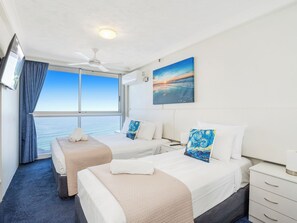 Enjoy ocean views from the large window in this stylish room featuring two beds with crisp linens and a beautiful painting above.