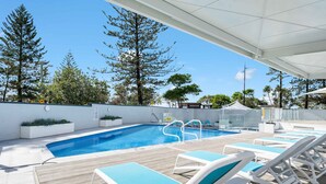 A swimming pool with lounge chairs and a covered area. - 28th Floor Oceanfront Bliss in Surfers Paradise (Surfers Paradise)