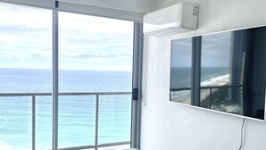 A bedroom with a bed, a ceiling fan, a window with a view of the ocean, and a mounted TV. - 28th Floor Oceanfront Bliss in Surfers Paradise (Surfers Paradise)