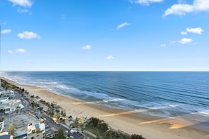 Une vue côtière comprenant une plage, l’océan et des bâtiments le long du rivage.