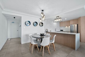 A modern kitchen with a central island, white chairs, and a dining table.