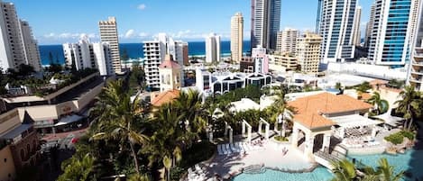 A resort with a large pool, palm trees, and high-rise buildings in the background.