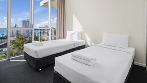 A hotel room with two beds, large windows, and a view of the city.