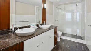 Un baño moderno con dos lavamanos, ducha y cabina de ducha acristalada.