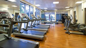 Un gimnasio con cintas de correr, bicicletas estáticas y máquinas de pesas.