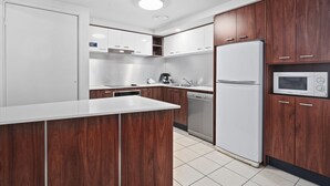 Una cocina moderna con armarios de madera, encimeras blancas, microondas integrado y lavavajillas.