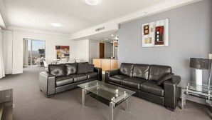 Un salon moderne avec deux canapés en cuir noir, une table basse en verre et une décoration minimaliste.