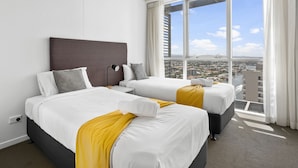 A hotel room with two beds, a large window with a city view, and a modern headboard.