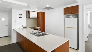 A modern kitchen with a white countertop, stainless steel sink, and wooden cabinets.